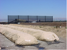 Judge Netting Barrier Specialists: A group of tarps serving as barrier and netting solutions on a dirt road.