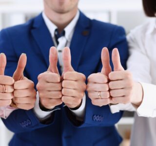 Three business professionals giving a thumbs up, focusing closely on their golf netting.