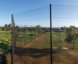 Judge Netting Barrier Specialists: A panoramic view of a golf course from the top of a fence with driving range netting.