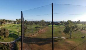 Judge Netting Barrier Specialists: A panoramic view of a golf course from the top of a fence with driving range netting.