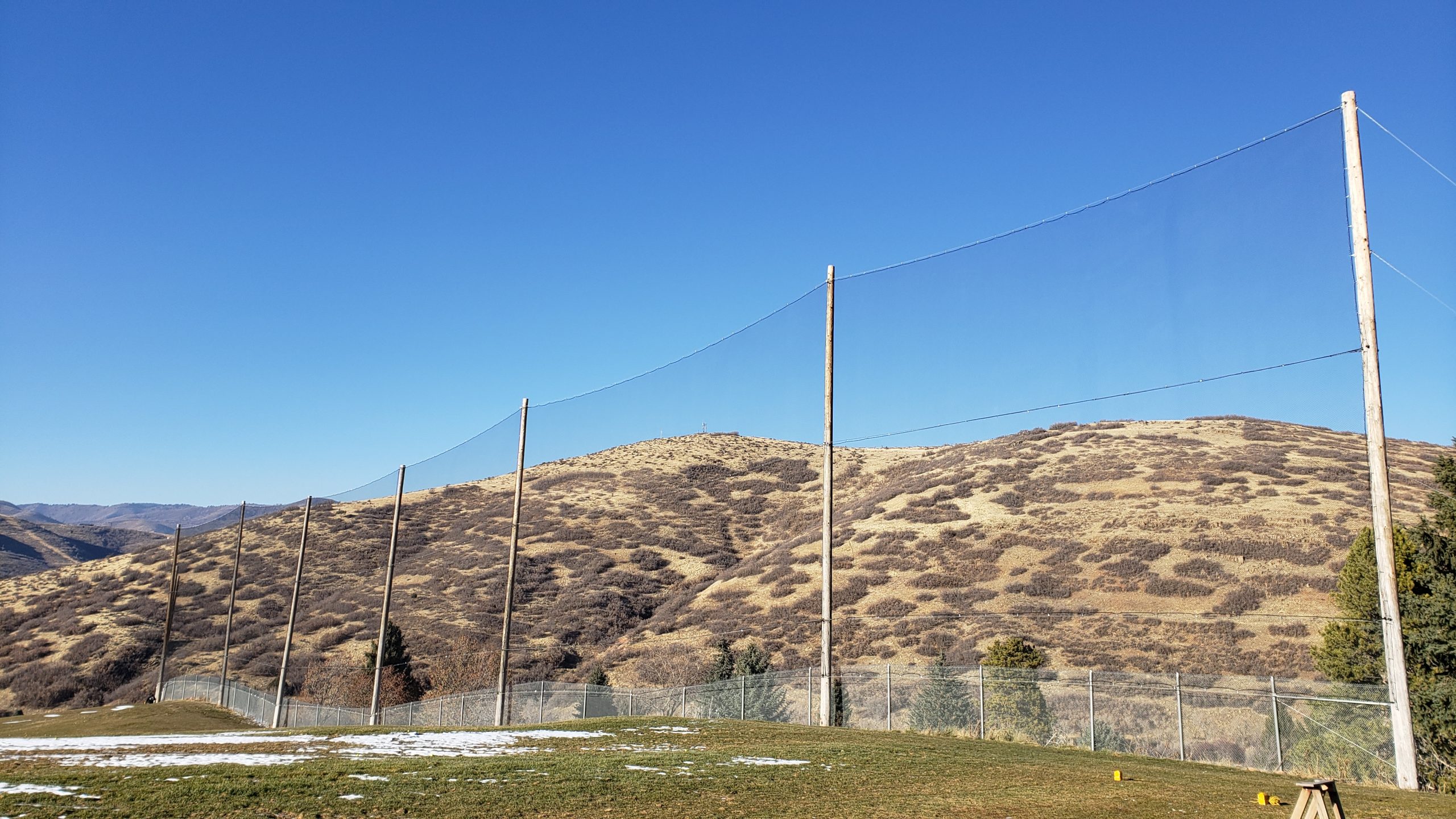 Judge Netting Barrier Specialists: A grassy field with netting serving as a golf course netting barrier.