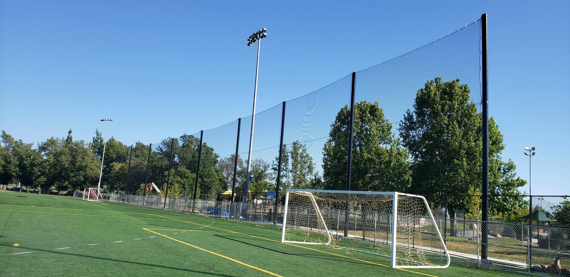 Judge Netting Barrier Specialists: A soccer field with a goal and golf course netting barriers in the middle of it.