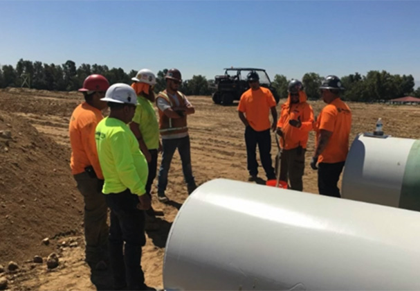 Judge Netting Barrier Specialists: Construction workers in safety gear attending an employment opportunities briefing at an outdoor worksite.