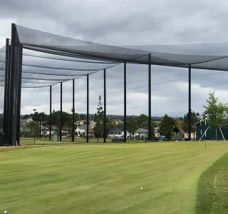 New fully enclosed driving range with tall steel poles and safety netting at Maggie Hathaway Golf Course in Los Angeles