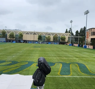 Wide view of the UCLA Spalding football practice field showing the new net barriers protecting the surrounding dormitory buildings