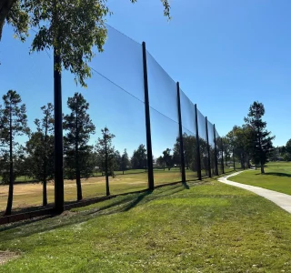 The completed driving range netting barrier stretching the length of the range at Almaden Golf & Country Club, with 1″ mesh polyester netting on black composite poles.
